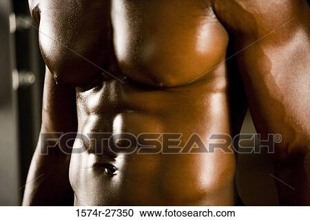 Stock Image - Midsection of a shirtless man after working out in the gym. Fotosearch