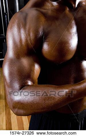Stock Photograph - Midsection of a young man flexing muscles in the gym. Fotosearch