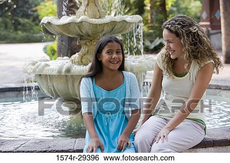 Mother and daughter sitting together by water fountain View Large Photo Image Stock Photograph - Mother and daughter sitting together by water fountain. Fotosearch