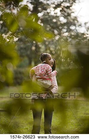 Mother carrying her daughter at park View Large Photo Image Stock Image - Mother carrying her daughter at park. Fotosearch