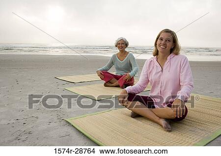 Mother exercising with daughter on a mat at the beach View Large Photo Image Picture - Mother exercising with daughter on a mat at the beach. Fotosearch