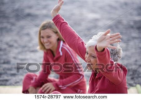 Stock Photo - Mother exercising with her daughter at the beach. Fotosearch