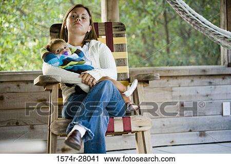 Stock Image - Mother holding her son on armchair in a house. Fotosearch