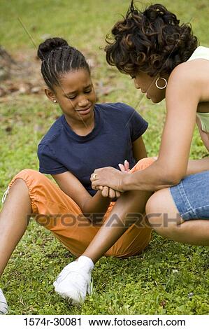 Stock Image - Mother looking palm of her daughter at park. Fotosearch