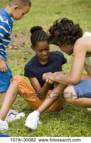 Stock Image - Mother looking palm of her daughter at park. Fotosearch