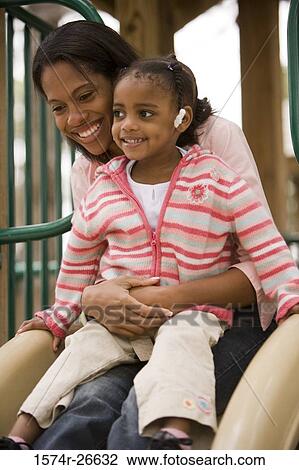 Mother playing with her daughter on slide at park View Large Photo Image Stock Image - Mother playing with her daughter on slide at park. Fotosearch