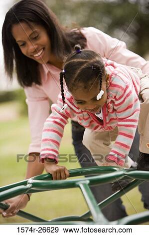 Mother playing with her daughter on jungle gym at park View Large Photo Image Stock Photo - Mother playing with her daughter on jungle gym at park. Fotosearch