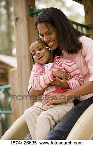 Mother playing with her daughter on slide at park View Large Photo Image Stock Photography - Mother playing with her daughter on slide at park. Fotosearch