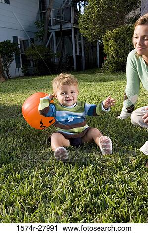 Stock Image - Mother playing with her son in lawn with a toy. Fotosearch