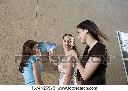Stock Image - mother with her daughters holding color swatches against wall. Fotosearch