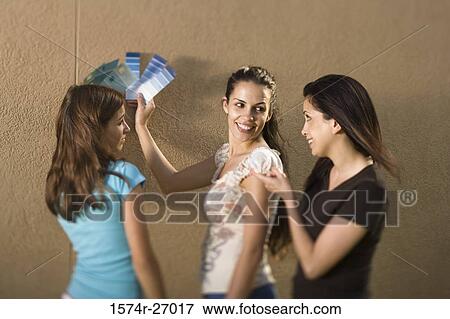 Stock Photo - mother with her daughters holding color swatches against wall. Fotosearch