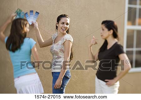 Stock Photography - mother with her daughters holding color swatches against wall. Fotosearch