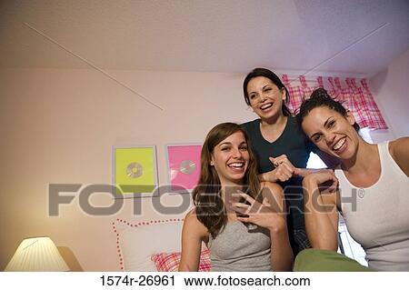 Stock Image - Mother with her daughters smiling in bedroom. Fotosearch