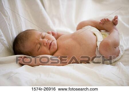 Stock Photograph - Newborn baby lying on bed. Fotosearch