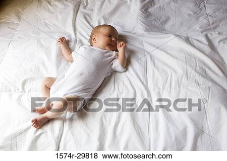 Stock Photo - Newborn baby sleeping on the bed. Fotosearch