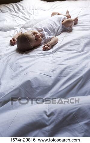 Stock Photograph - Newborn baby sleeping on the bed. Fotosearch