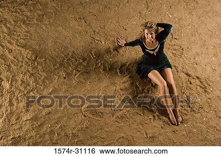Overhead view of a cheerful young woman lying on sand View Large Photo Image Stock Photograph - Overhead view of a cheerful young woman lying on sand. Fotosearch