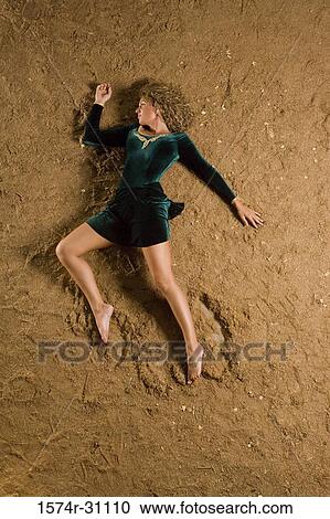 Stock Image - Overhead view of a young woman lying on sand. Fotosearch