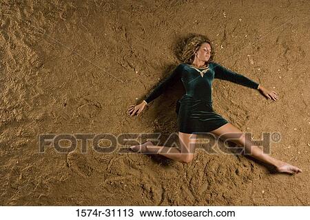 Stock Image - Overhead view of a young woman lying on sand. Fotosearch