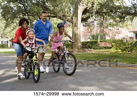 Parents helping children to ride bicycles on the road View Large Photo Image Stock Photo - Parents helping children to ride bicycles on the road. Fotosearch