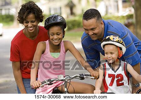 Parents helping their children to ride bicycles on the road View Large Photo Image Stock Photo - Parents helping their children to ride bicycles on the road. Fotosearch