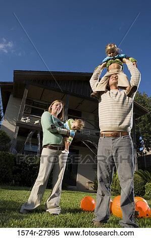 Stock Photography - Parents holding their children in front of a house. Fotosearch