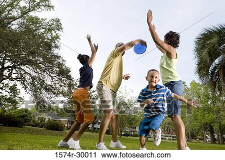 Parents playing plastic disk with their children at park View Large Photo Image Stock Image - Parents playing plastic disk with their children at park. Fotosearch