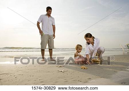 Parents playing with daughter on the beach View Large Photo Image Stock Photo - Parents playing with daughter on the beach. Fotosearch