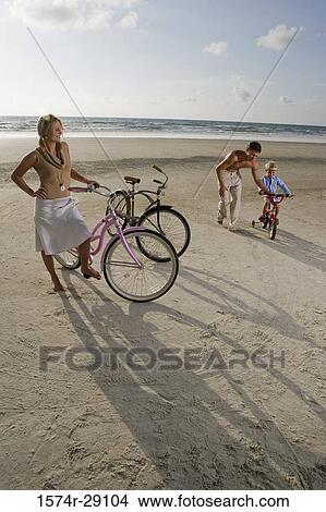 Picture - Parents with son riding cycle at the beach. Fotosearch