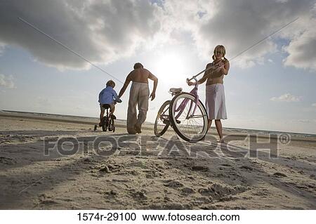 Stock Image - Parents with son riding cycle at the beach. Fotosearch