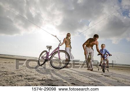 Parents with son riding cycle at the beach View Large Photo Image Stock Photo - Parents with son riding cycle at the beach. Fotosearch