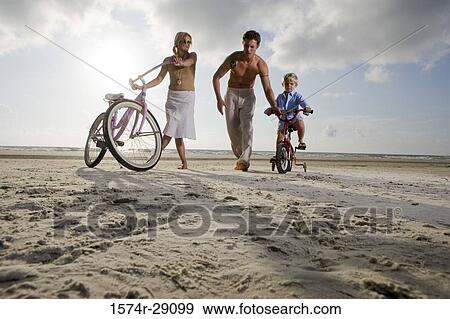 Parents with son riding cycle at the beach View Large Photo Image Stock Photo - Parents with son riding cycle at the beach. Fotosearch