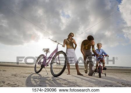 Parents with son riding cycle at the beach View Large Photo Image Stock Photograph - Parents with son riding cycle at the beach. Fotosearch