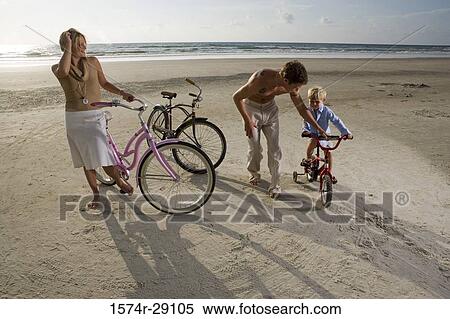 Stock Photography - Parents with son riding cycle at the beach. Fotosearch