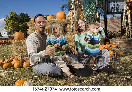 Picture - Parents with their children sitting by straw bundle. Fotosearch