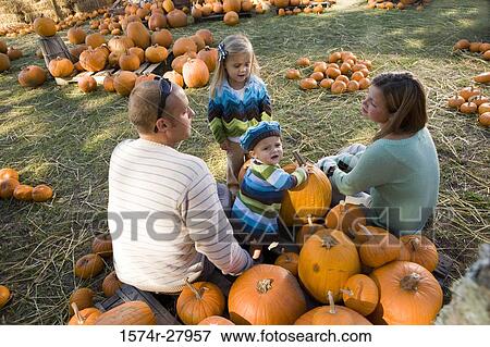 Stock Photo - Parents with their children sitting amid pumpkins. Fotosearch
