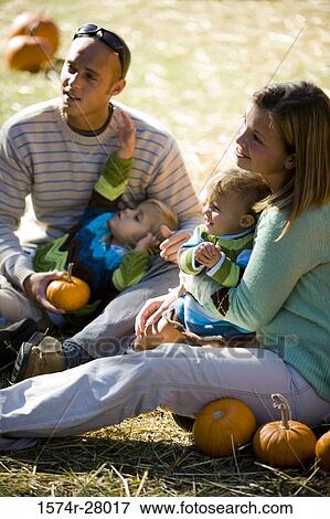 Parents with their children sitting amid pumpkins View Large Photo Image Stock Photo - Parents with their children sitting amid pumpkins. Fotosearch