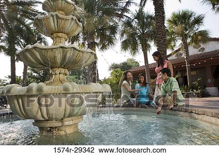 Stock Image - People sitting together by a water fountain. Fotosearch