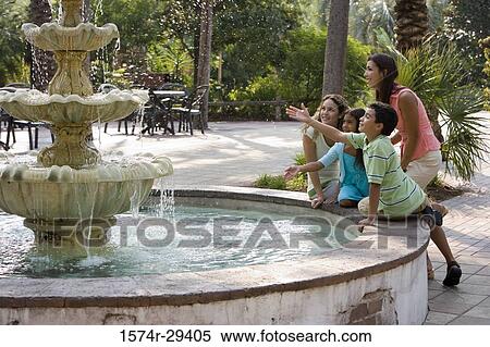 Stock Photography - People sitting together by a water fountain. Fotosearch