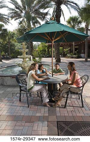 People sitting together on chairs by a water fountain View Large Photo Image Stock Photo - People sitting together on chairs by a water fountain. Fotosearch