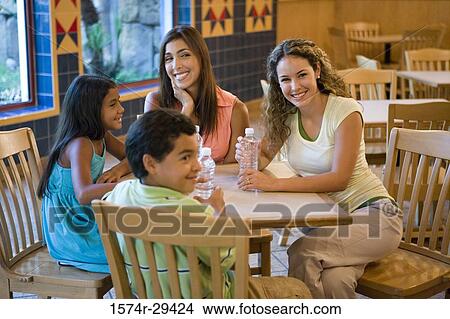 Picture - People sitting together on chairs by table in hotel. Fotosearch