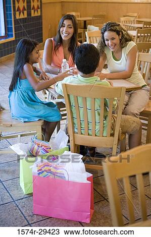 Stock Image - People sitting together on chairs by table in hotel. Fotosearch