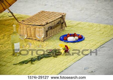 Picnic basket with beverage and flowers on mat at the beach View Large Photo Image Stock Photo - Picnic basket with beverage and flowers on mat at the beach. Fotosearch