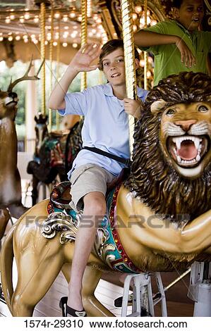 Portrait a teenage boy sitting on a carousel lion and waving hand View Large Photo Image Stock Image - Portrait a teenage boy sitting on a carousel lion and waving hand. Fotosearch