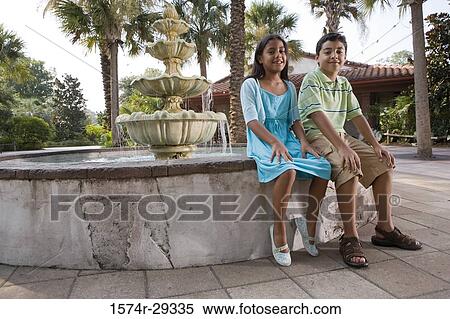 Portrait of a boy and girl sitting together by water fountain View Large Photo Image Stock Photography - Portrait of a boy and girl sitting together by water fountain. Fotosearch