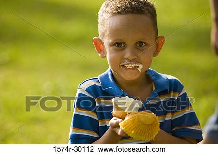 Portrait of a boy holding a cupcake at park View Large Photo Image Stock Image - Portrait of a boy holding a cupcake at park. Fotosearch