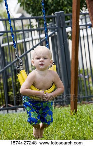 Stock Photo - Portrait of a boy playing on swing at park. Fotosearch