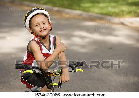 Portrait of a boy sitting on bicycle on the road View Large Photo Image Stock Photograph - Portrait of a boy sitting on bicycle on the road. Fotosearch