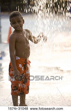 Portrait of a boy standing under a shower View Large Photo Image Stock Photo - Portrait of a boy standing under a shower. Fotosearch