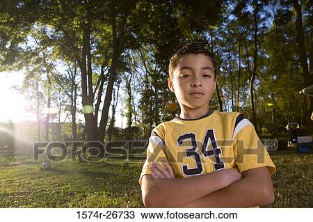 Stock Image - Portrait of a boy with arms crossed at forest. Fotosearch